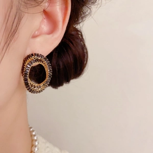 Gros plan de boucles d'oreilles dorées avec cristaux noirs portées par un mannequin