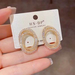Détail de boucles d'oreilles ovales dorées avec zircone et tiges en argent S925