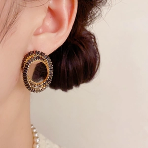 Détail d'un mannequin portant des boucles d'oreilles tournesol avec cristaux noirs