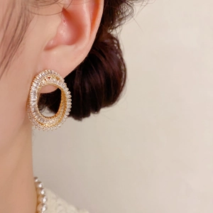 Détail de boucles d'oreilles ovales de luxe serties de zircons brillants sur base dorée