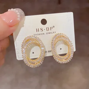 Vue macro de boucles d'oreilles ovales dorées avec zircons et tige en argent 925
