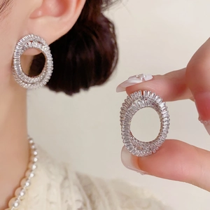 Détail de boucles d'oreilles doubles cercles serties de strass brillants argentés