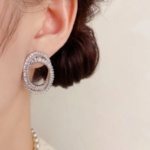 Gros plan de boucles d'oreilles doubles ovales avec zircons brillants sur l'oreille