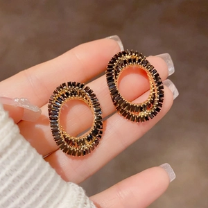 Vue macro de boucles d'oreilles ovales dorées avec cristaux noirs rayonnants