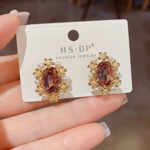 Close-up of vintage geometric earrings with fuchsia gemstones, gold flowers and pearls