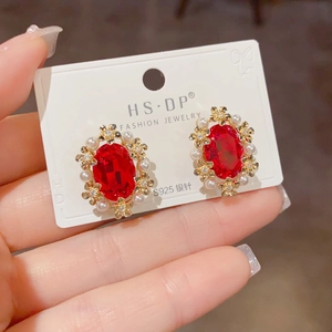 Macro shot of vintage style earrings with red gemstone, pearls, and S925 silver needles