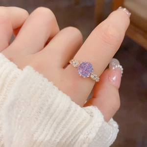Detailed view of gold ring featuring lavender cubic zirconia on index finger
