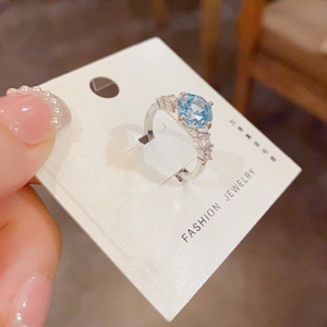 Detailed view of light blue round zircon ring with silver prong setting and side stones