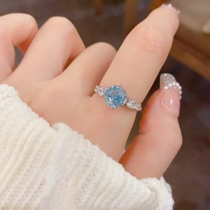 Macro view of blue rose-cut zircon ring on finger with elegant white knit sleeve