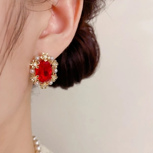 Close-up of vintage gold petal earring with a large red gemstone and small pearls