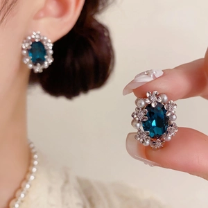 Detailed close-up of vintage flower earrings with dark blue gemstone and pearls