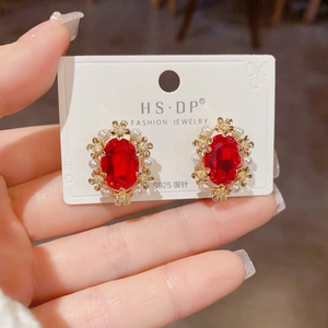 Macro view of S925 silver needle earrings with red gemstone and pearl floral design
