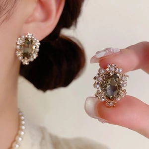 Detail showing vintage metal flower earrings with grey gemstones and small pearls