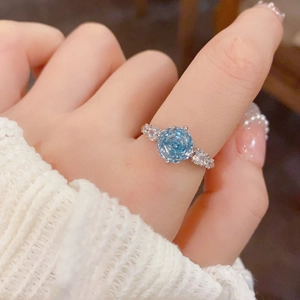 Detailed close-up of a silver ring with a blue rose-shaped stone and zircon accents