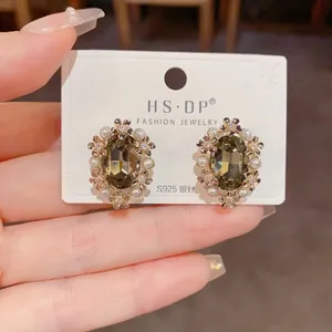 Close-up of S925 silver stud earring with smoky grey gem and pearl floral detail
