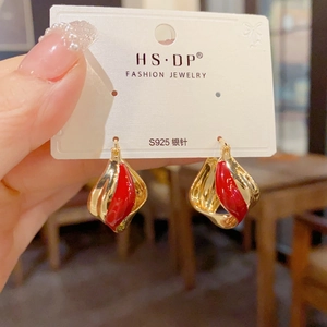 Detail of twisted gold metal earrings with red enamel drip and S925 silver needles