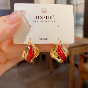 Close-up of twisted gold hoops with red enamel and S925 silver posts on card