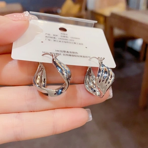 Detailed shot of twisted silver-colored metal earrings with S925 silver needles