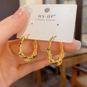 Detail der eleganten goldenen Creolen mit Wellenstruktur auf einer Schmuck-Displaykarte