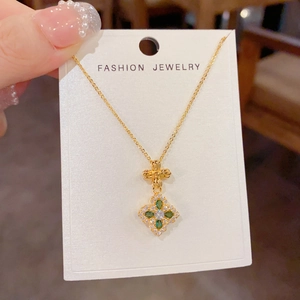 Elegant gold necklace featuring a four-leaf flower pendant with green and white zircons