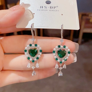 Detalle de pendientes vintage de corazón con cristales verdes, perlas y borlas