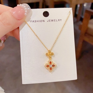 Close-up of golden four-leaf flower pendant necklace with orange and white zircons