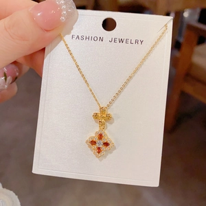 Detailed macro view of four-leaf clover pendant with red marquise stones and gold chain