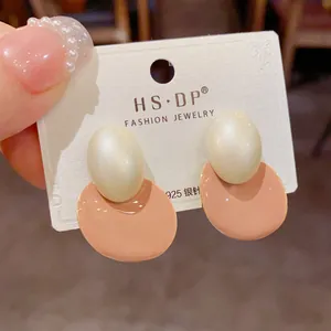Détail de boucles d'oreilles en argent S925 avec perle crème et émail rose élégant