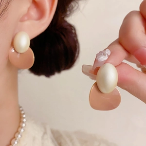 Détail de boucles d'oreilles vintage françaises avec contraste pêche et perle d'imitation