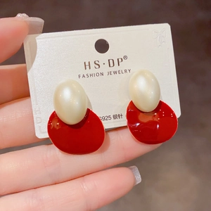 Détail de boucles d'oreilles géométriques rouges et crème avec tiges en argent S925 sur carte