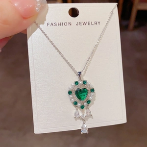 Detalle de collar bohemio con corazón de gema verde, perlas y circonitas de gota