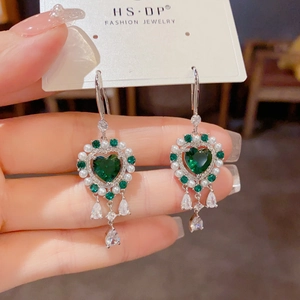 Primer plano de aretes de corazón vintage con cristales esmeralda y perlas blancas