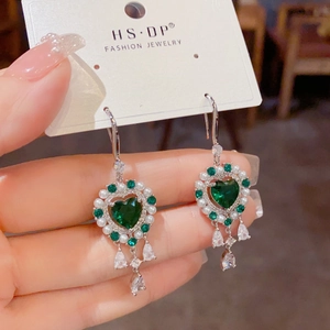 Detalle de pendientes de esmeralda corazón con perlas y borlas de gotas de agua