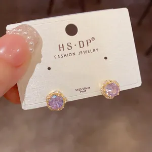 Détail de boucles d'oreilles en argent S925 avec zircon violet et cadre fleur dorée