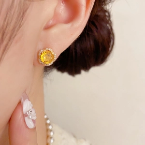 Boucles d'oreilles fleur exquises avec zircon jaune et base dorée portées par mannequin