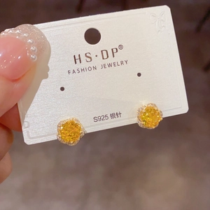 Gros plan de boucles d'oreilles fleurs en zircon jaune avec tige en argent S925 sur carte