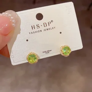 Détail de boucles d'oreilles fleur en argent S925 avec zircon vert et pétales blancs