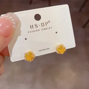 Gros plan sur boucles d'oreilles fleur jaune en argent S925 avec zircons scintillants