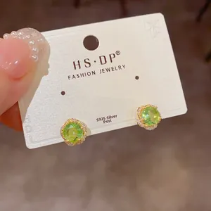 Détail macro des boucles d'oreilles fleur zircon vert avec tiges en argent S925