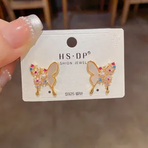 Detail of S925 silver butterfly earrings with colorful zircons and a white pearl accent