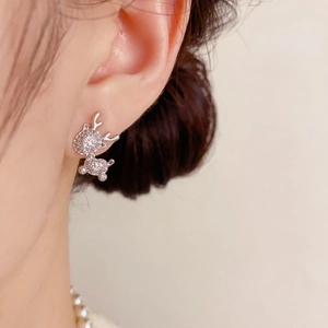 Close-up of a sparkling crystal reindeer stud earring worn elegantly on a model ear
