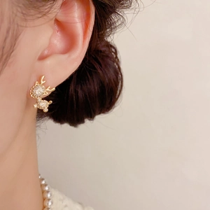 Detailed close-up of a delicate gold reindeer earring with sparkling white crystals