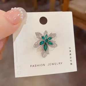 Vue détaillée de la broche feuille d'érable avec gemmes vertes et placage en or