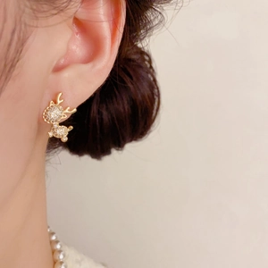 Close-up of golden reindeer stud earrings with sparkling crystals worn by a model