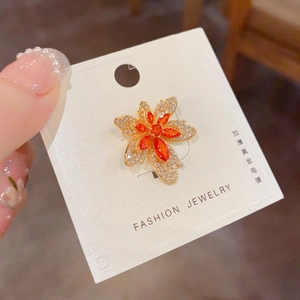 Détail d'une broche feuille d'érable dorée sertie de cristaux et gemmes oranges