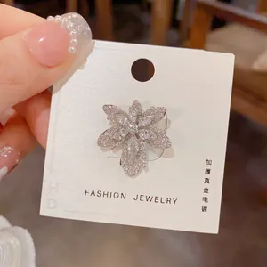 Détail macro d'une broche feuille d'érable argentée avec zircons et placage en or épais