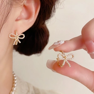 Elegantes pendientes de lazo dorado con perlas y cristales en modelo y detalle