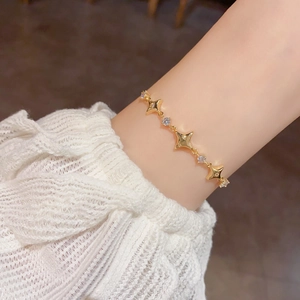 Close-up of a gold star-shaped bracelet with cubic zirconia on a white lace sleeve