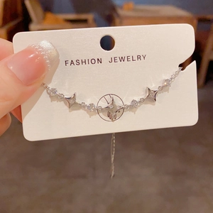 Close-up of a silver star charm bracelet with sparkling round crystals on a display card