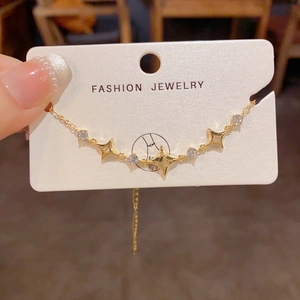 Detail of gold star bracelet with cubic zirconia charms and extension chain on card